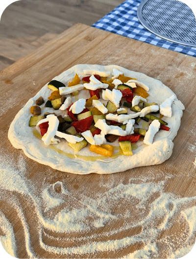 Adding fresh local ingredients to pizza during a cooking class in Umbria